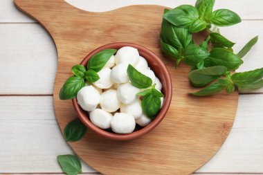 Lezzetli mozzarella peyniri topları kasede ve fesleğen açık ahşap masada, düz yerde