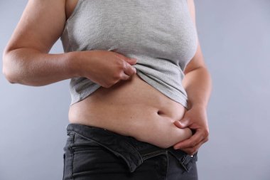 Hafif arka planda aşırı göbek yağı olan kadın, yakın plan. Aşırı kilolu