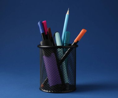 Koyu mavi arkaplanda kalem tutacağında farklı bir kırtasiye