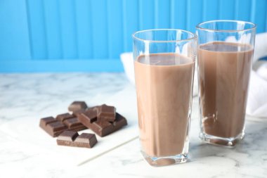 Bardakta çikolatalı süt ve beyaz mermer masada malzeme, yakın plan.