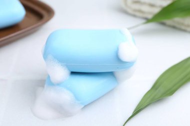 Beyaz masadaki köpüklü sabun çubukları, yakın plan.