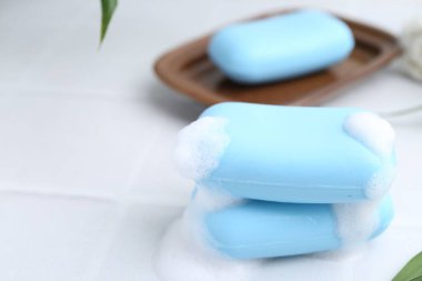 Beyaz masadaki köpüklü sabun çubukları, yakın plan. Metin için boşluk