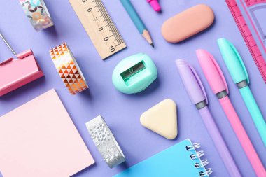 Menekşe arkaplan üzerinde kalemler ve diğer kırtasiye düz yatıyordu