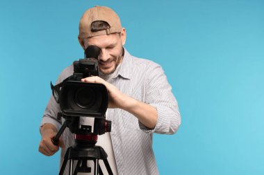 Açık mavi arkaplanda profesyonel video kamerası olan adam, metin için boşluk