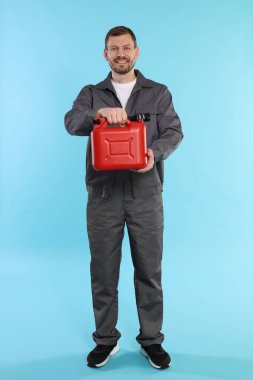 Açık mavi arka planda plastik kutu tutan adam.