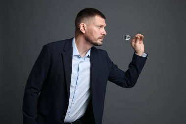 Hedef alınıyor. Gri arkaplanı hedefleyen dartlı adam.