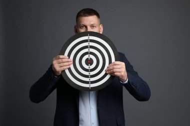 Hedef alınıyor. Gri arka planda dart tahtası olan adam.