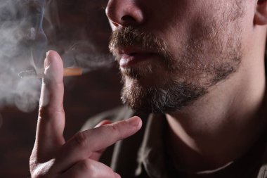 Arka planda sigara içen adam, yakın plan.