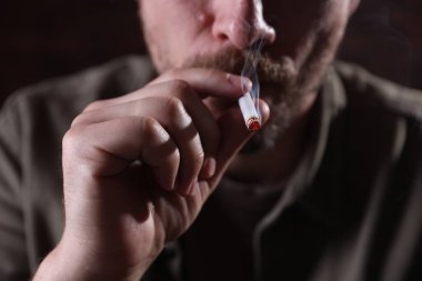 Arka planda sigara içen adam, yakın plan.