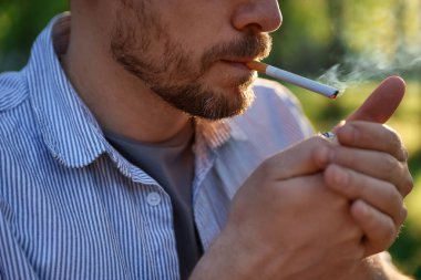 Sigarayı çakmakla yakan adam, yakın plan.
