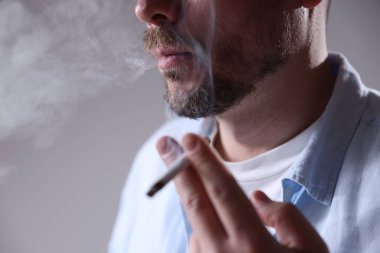 Arka planda sigara içen adam, yakın plan.