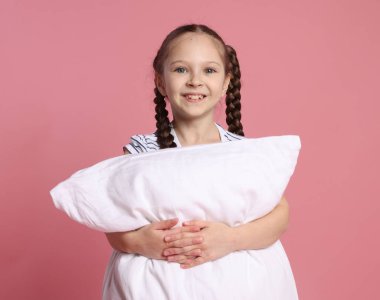 Pembe arka planda yastığı olan tatlı bir kız.