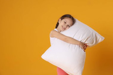 Turuncu arka planda yastığı olan tatlı bir kız. Metin için boşluk