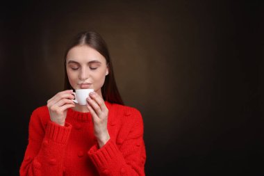 Kahverengi arka planda fincandan kahve içen kadın. Metin için boşluk