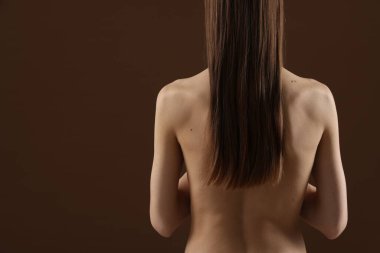 Kahverengi arka planda çıplak bir kadın. Metin için boşluk