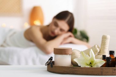 Kadın kuaförde dinleniyor, spa ürünlerine ve çiçeklere odaklanıyor