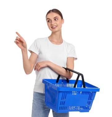 Plastik alışveriş sepetli kadın beyaz arka plandaki bir şeyi işaret ediyor.