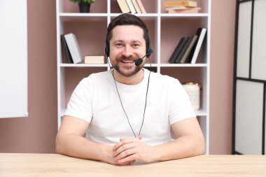 Gülümseyen çevrimiçi hoparlör. İçerideki masada ağlar, web kamerasından görüntü.