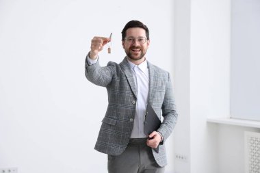 Emlakçının elinde evin anahtarı, anahtarlık ve pano var.