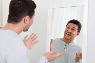 Yakışıklı adam aynada kendine bakıyor.