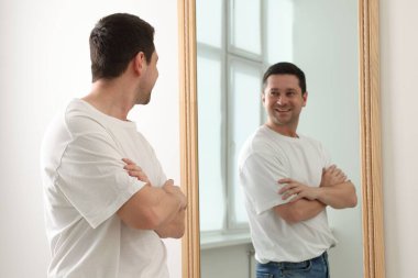 Yakışıklı adam aynada kendine bakıyor.