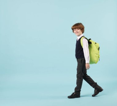 Açık mavi arka planda sırt çantası olan sevimli okul çocuğu, mesaj için yer var.