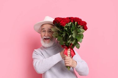 Pembe arka planda kırmızı gül buketi olan son sınıf öğrencisi.