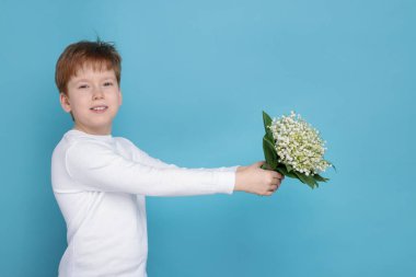 Açık mavi arka planda, vadideki güzel çiçekleri olan çocuk.