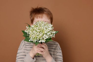 Kahverengi arka planda vadideki güzel çiçekleri olan bir çocuk.