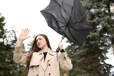 Kırık şemsiyeli bir kadın açık havada rüzgarla dövüşüyor, düşük açılı.