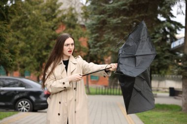 Şemsiyesi kırık bir kadın dışarıda rüzgarla savaşıyor.