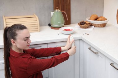 Mutfaktaki hamamböceklerine böcek ilacı sıkan kadın.