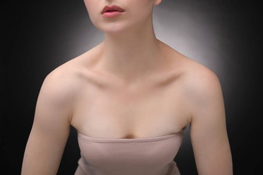 Güzel köprücük kemikleri ve siyah arka planda boynu olan kadın, yakın plan.