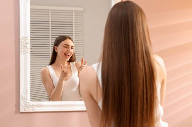 Güzel bir kadın aynada kendine bakıyor.