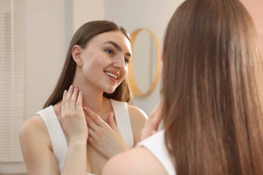 Güzel bir kadın aynada kendine bakıyor.