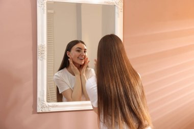 Güzel bir kadın aynada kendine bakıyor.