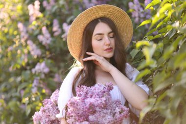 Leylak çiçeklerinin arasında güzel bir kadın ve açık havada bırakır