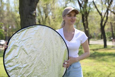 Güneşli bir günde yansıtıcısı olan bir kadın. Fotoğraf ekipmanları