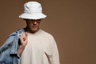 Kahverengi arka planda şık giyinmiş yakışıklı bir adamın modaya uygun portresi.