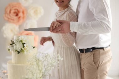 Evli çift içeride bıçakla lezzetli bir düğün pastası kesiyor.