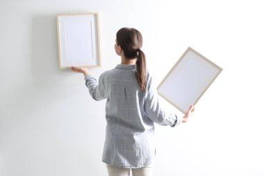 Beyaz duvara boş çerçeveler asan kadın, arka plan