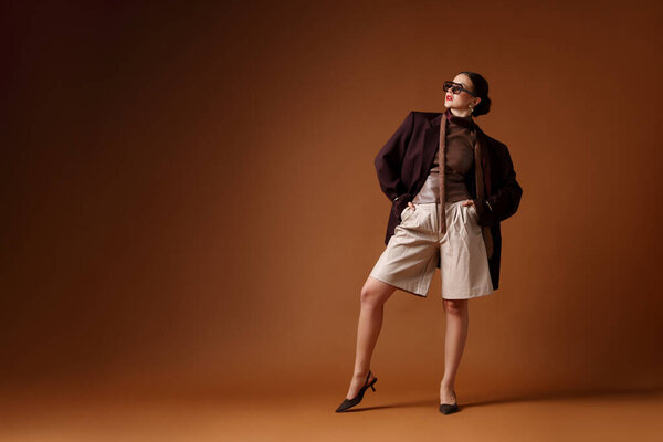 Молодая женщина в стильной одежде на коричневом фоне, пространство для текста