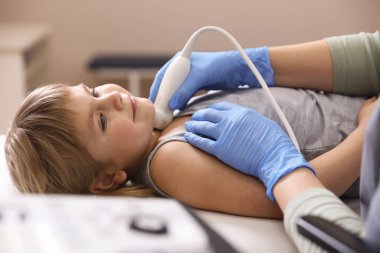 Sonograf, klinikte küçük kızın tiroid bezini ultrason muayenesi yapıyor.