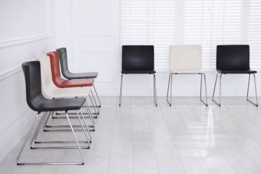 Bekleme odasındaki beyaz duvarın yanındaki renkli sandalyeler