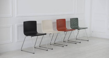 Bekleme odasındaki beyaz duvarın yanındaki renkli sandalyeler