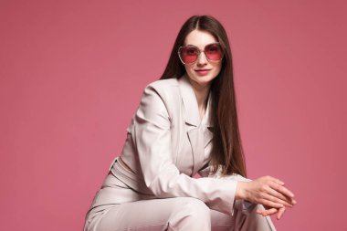 Pembe arka planda şık giyinmiş güzel bir kadının moda portresi.