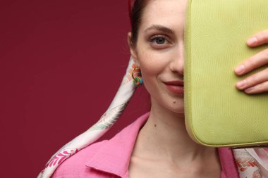 Koyu kırmızı arka planda şık giyinmiş bir kadın, yakın plan. Metin için boşluk