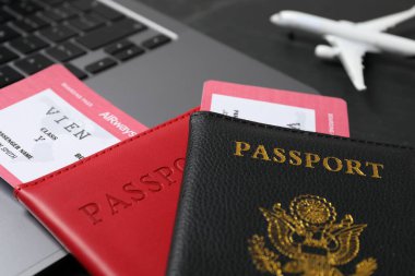 Pasaportlar, uçuş biletleri, uçak modeli ve laptop siyah masada, yakın plan.