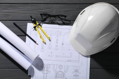 Farklı mühendislik çizimleri, sert şapka, gözlük, kalem ve ayırıcı gri ahşap masa, düz yatıyordu.