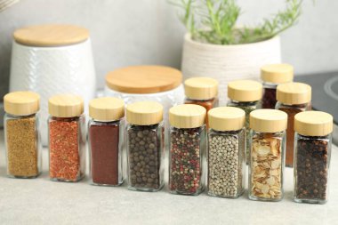 Açık gri masa üzerinde kavanozlarda çok farklı aromatik baharatlar var.